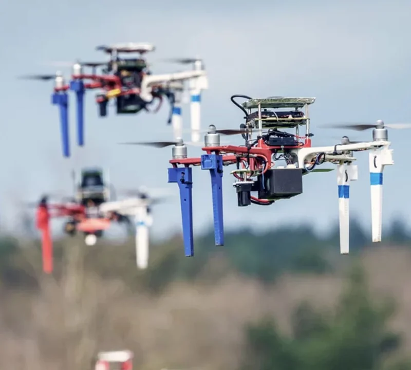 Several quadcopter drones flying at different distances in an outdoor field